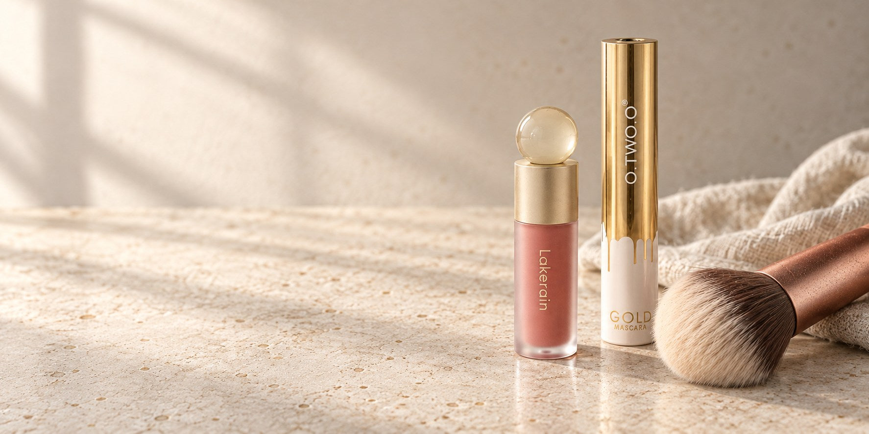 Liquid blush, mascara and a powder brush in natural window light